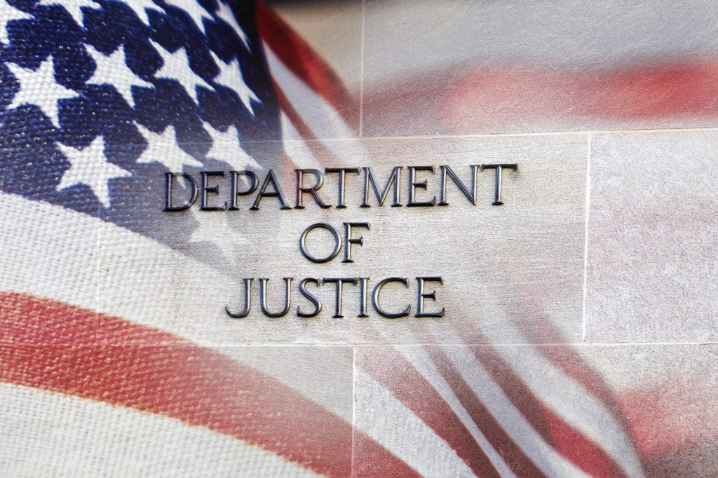 US DOJ sign against US flag