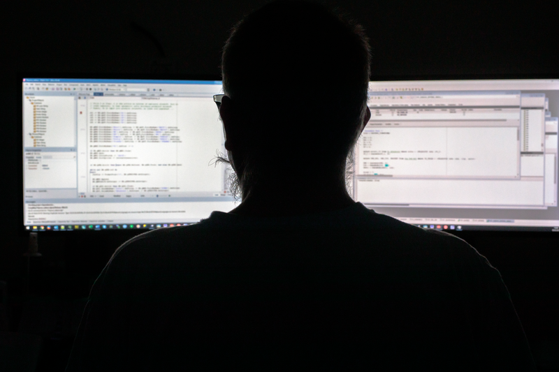 Person looking at two computer screens in the dark