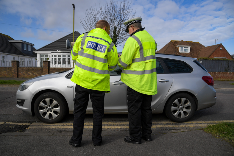 Two police officers looking down on a phone.
