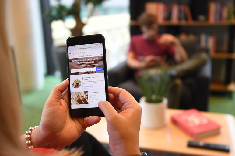 An online shopper uses the eBay mobile app in their living room