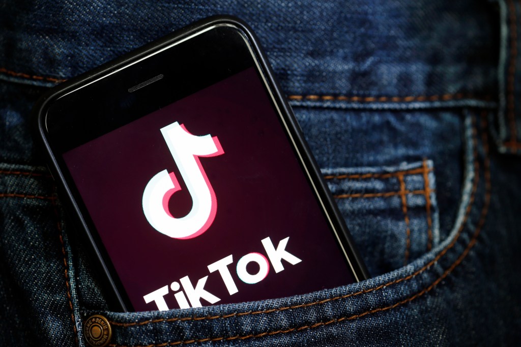 Tik Tok logo on phone screen in jeans pocket