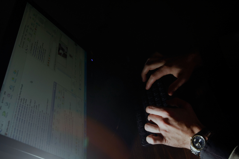 A man is writing on a laptop.
