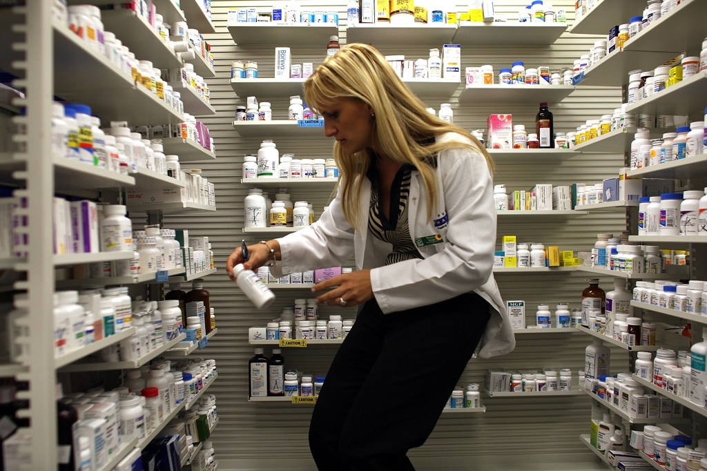 Image of a pharmacist stocking shelves with bottles of pills.