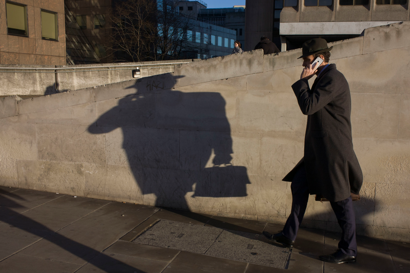 A man carrying a briefcase casting a shadow in front of him
