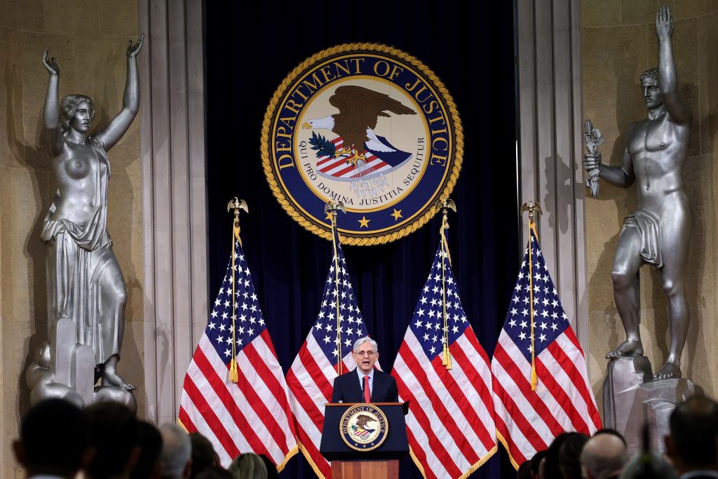 Image of the DOJ insignia and Attorney General Merrick Garland at a podium.