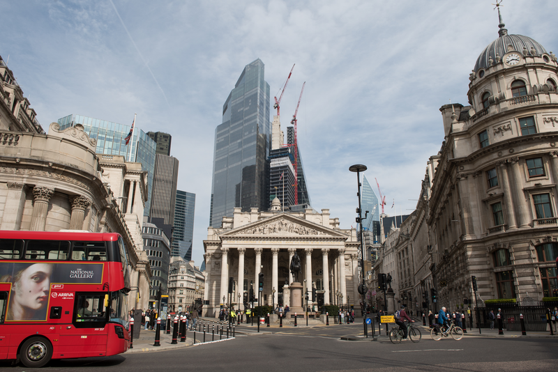 View of a red double decker bus at the Royal Exchange by the Bank of England at Bank with commercial skyscrapers