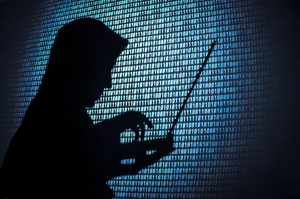 Image of the silhouette of a man on a computer against a digital background.