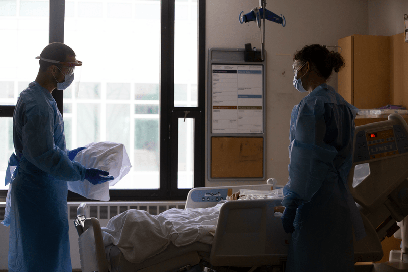 Two nurses administer care to a patient at a hospital.