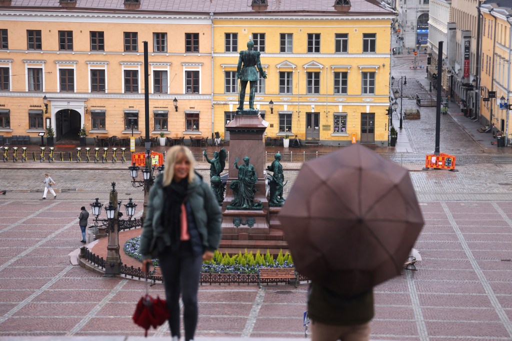 Visitors stand at Senate Square and a statue of Russian Emperor Alexander II in Helsinki, Finland.