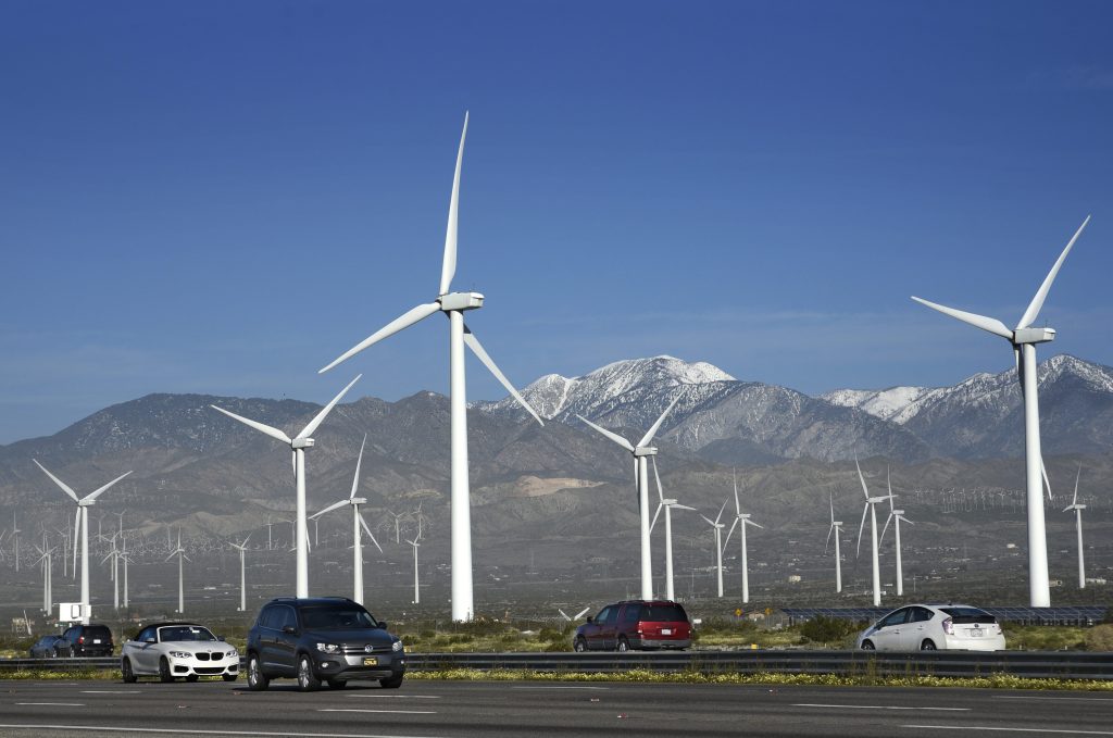 Image of cars passing a series of wind turbines.