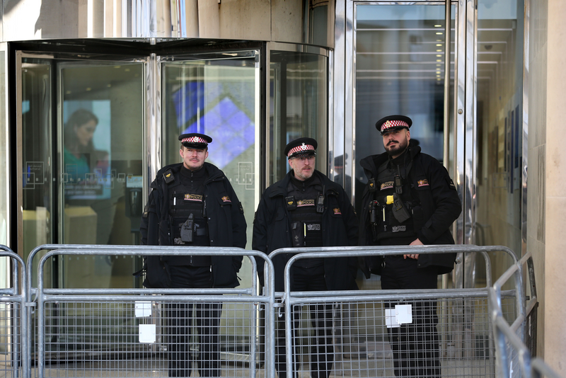 Police officers stand behind security barriers outside the London Stock Exchange.