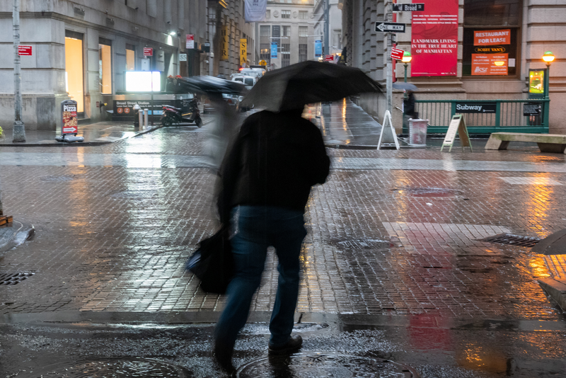 People walk through the morning rain by the New York Stock Exchange in New York City.