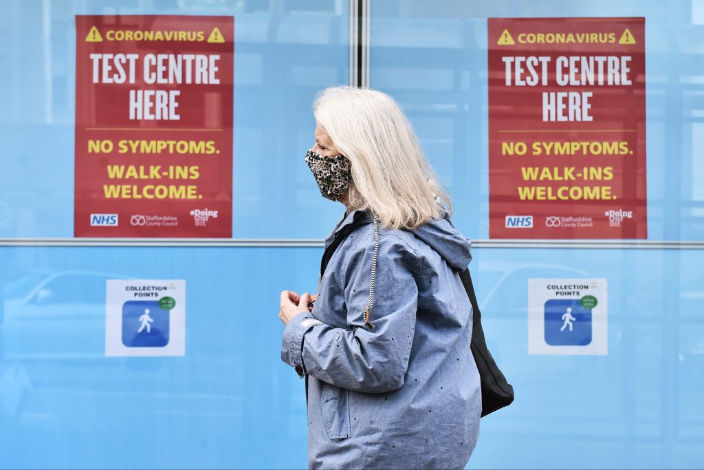 Woman in mask by Covid testing sign