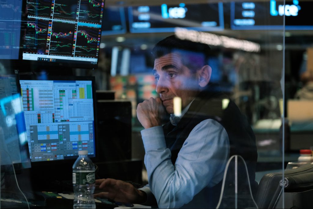 Image of a man trading stocks in front of several computers.