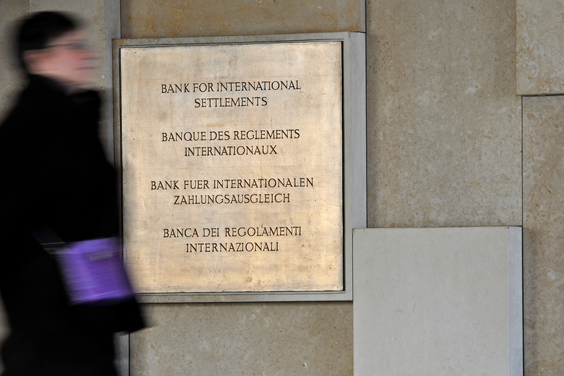 A woman walks past the plaque of the Bank for International Settlements (BIS)