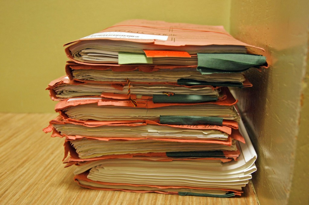 Image of a stack of paper files in folders.