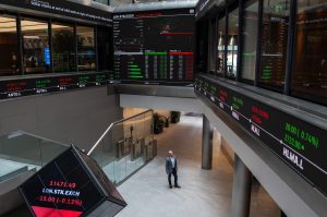 A member of staff poses next to trading boards at the London Stock Exchange