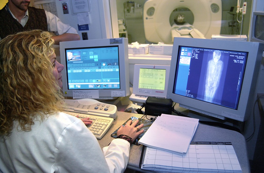 A photo of a woman clinician reading a CT scan on a computer screen