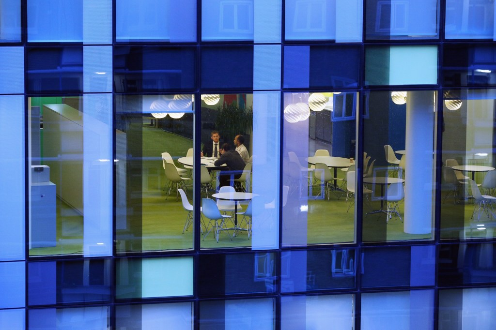People conducting a meeting in an office, seen from the outside.