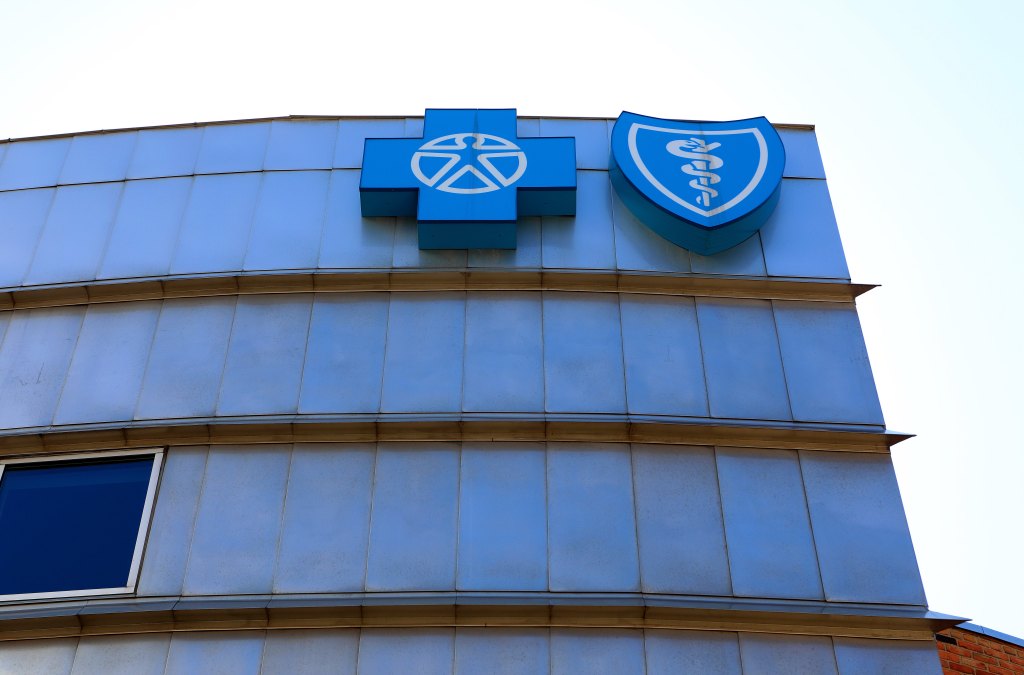 A photo of an office building with the Blue Cross Blue Shield logo on the top floor in blue against the glass windows.
