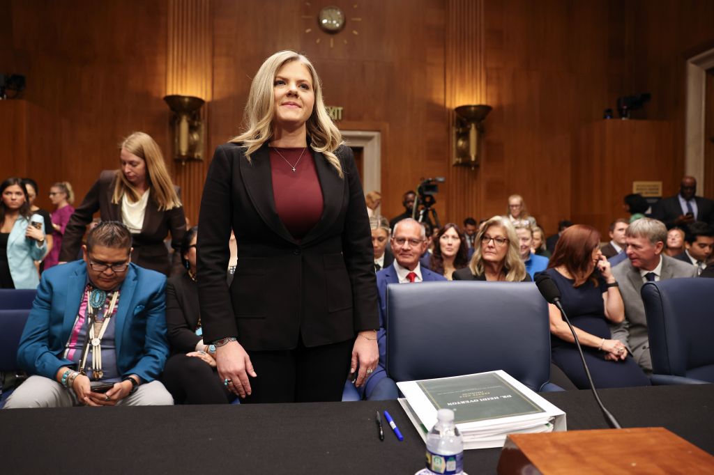 A photo of Heidi Overton, nominee for FDA Commissioner, standing with a crowd of seated people behind her at her Senate Finance Committee nomination hearing