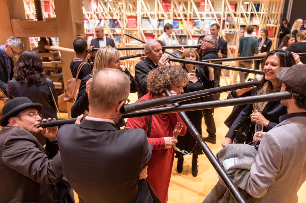 A photo of a crowd of men and women speaking and listening to each other long horns at the Frankfurt Book Fair.