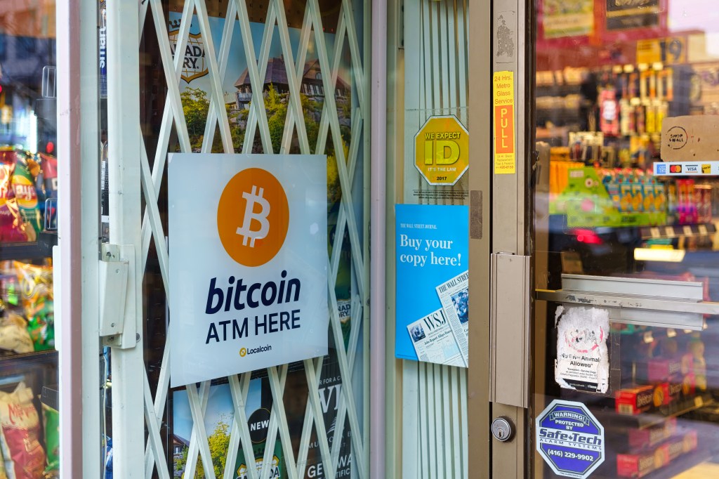 A sign advertising a Bitcoin ATM machine. The small business is located in downtown Toronto.
