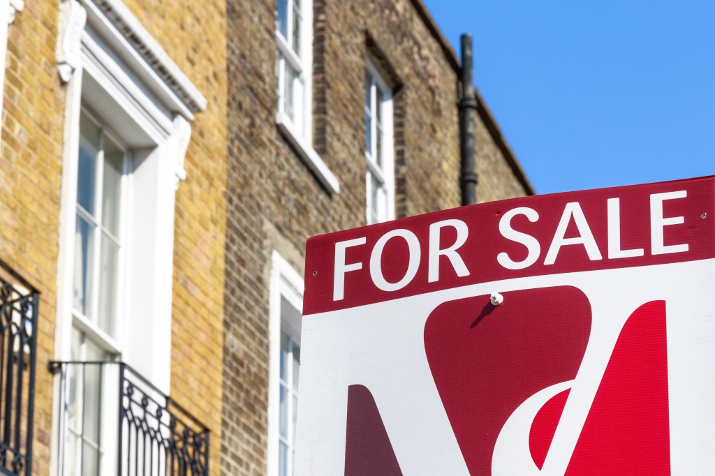 For Sale property agency sign posted outside English terraced houses.