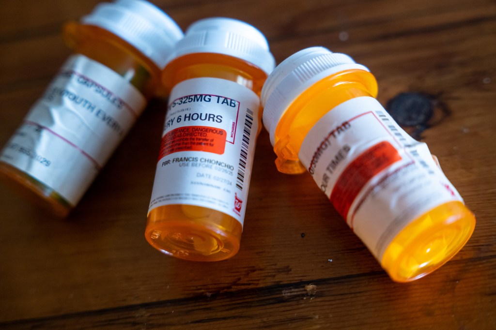 A photo of 3 prescription drug bottles laying sideways on a table.