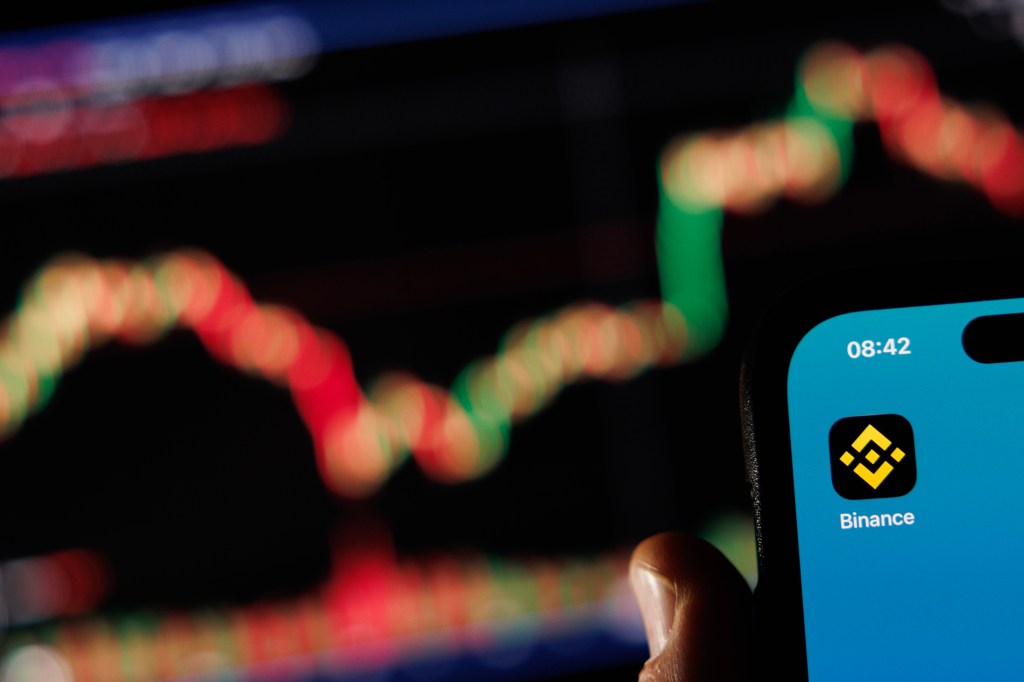 the Binance logo is displayed on a phone screen adjacent to an image from a crypto exchange on a laptop