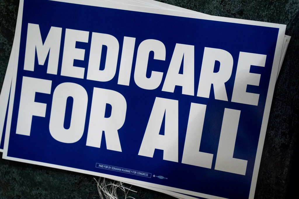 A blue sign with white border displaying "Medicare FOR ALL" in white words.