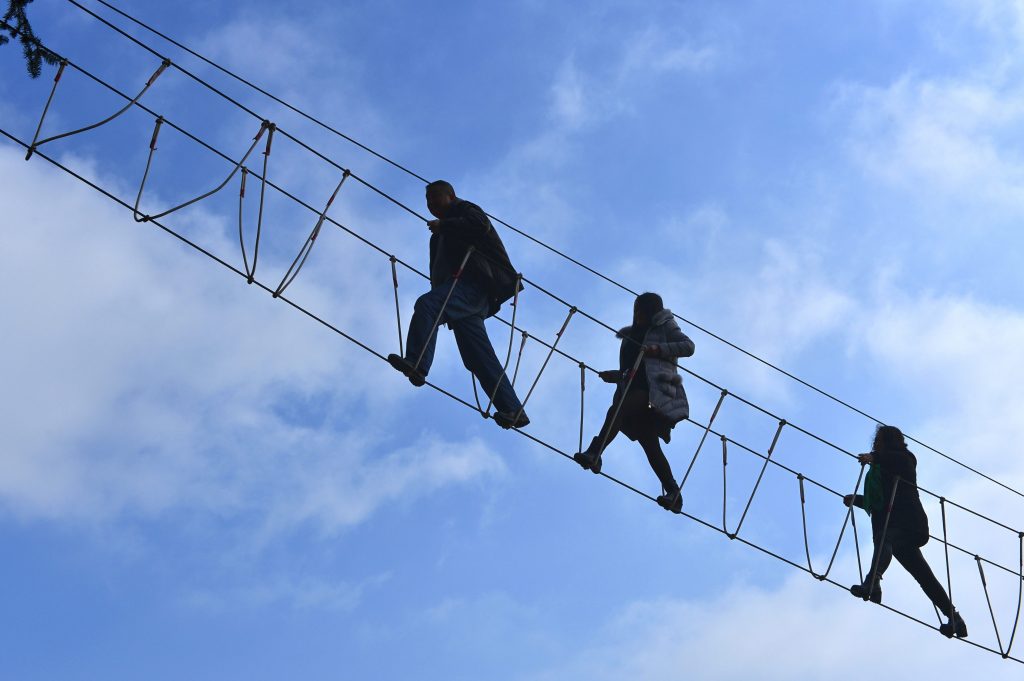 Tourists walk on the aerial cables bridge at the tea park in Enshi Tujia and Miao Autonomous Prefecture, Hubei Province of China.