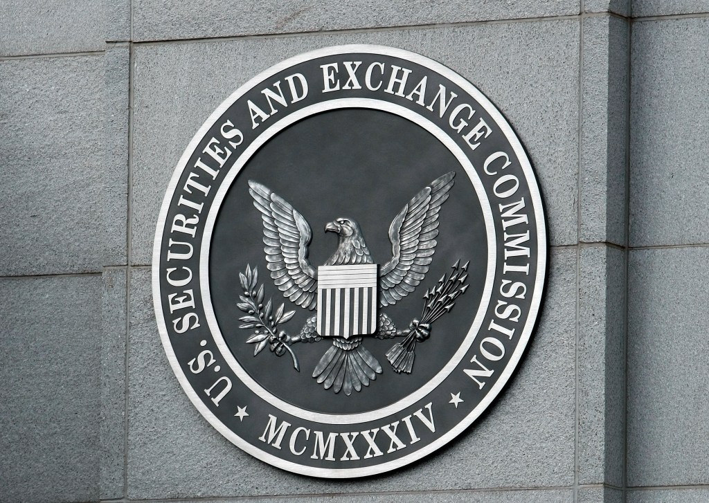 A black and white photo of the seal of the Securities and Exchange Commission mounted on a gray stone wall at its headquarters.