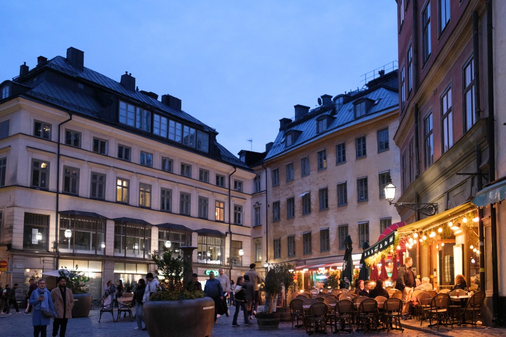 View of Jarntorget Square in the historic center with people milling about and some seated outdoors at restaurants in Gamla Stan on September 18, 2026 in Stockholm, Sweden