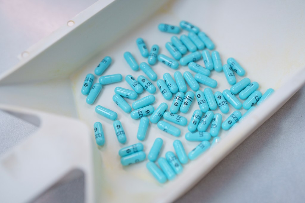 A photo of several blue prescription drug capsules in a white pharmacist tray.