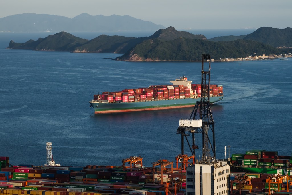 Image of cargo containers stacked on a shipping vessel in the water.