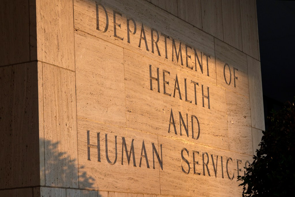 A photo of the words "Department of Health and Human Services" on a stone wall illuminated by the sun.