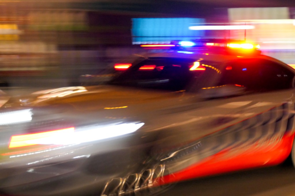 A BMW Series 7 vehicle of the NSW Police Highway Patrol with siren going and emergency lights flashing heads towards Bondi Beach